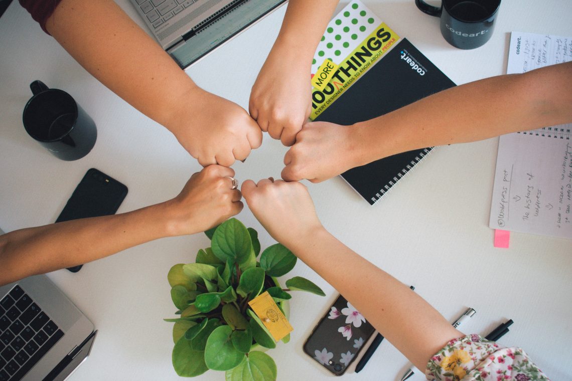 Five persons giving fistbump after successful cooperation
