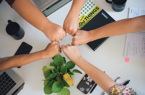 Five persons giving fistbump after successful cooperation